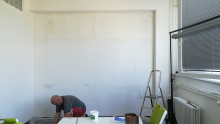 Příprava na výmalbu nové kanceláře, odstranění původního hnědého nátěru za projekčním plátnem